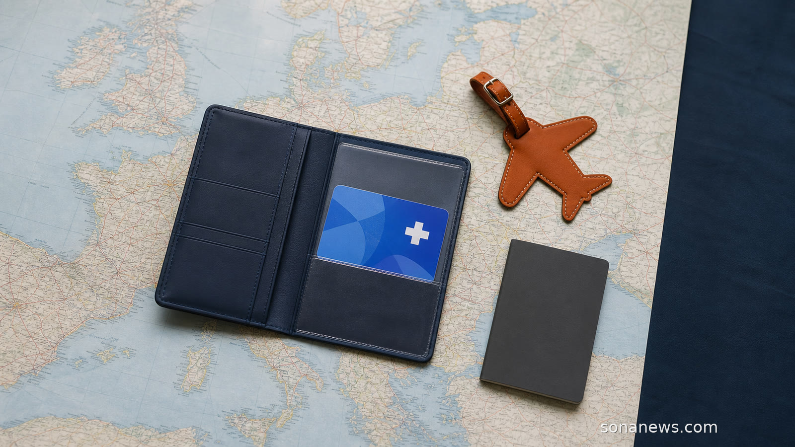Tarjeta sanitaria azul en una cartera de viaje sobre un mapa europeo, separada de una etiqueta de equipaje y un cuaderno de seguro.
