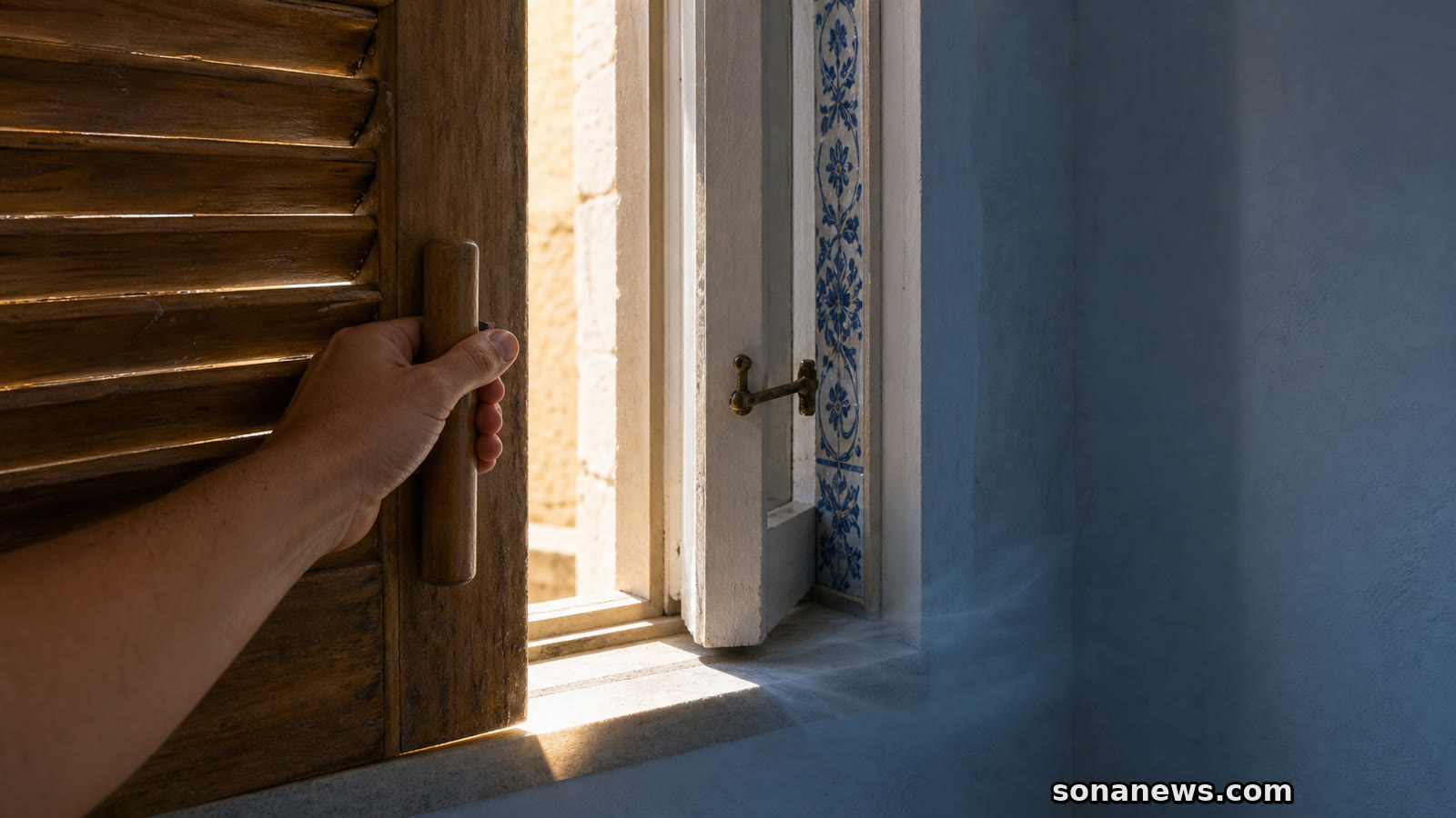 Mão fecha uma persiana exterior diante do sol forte, mantendo sombreada uma janela com azulejos portugueses.